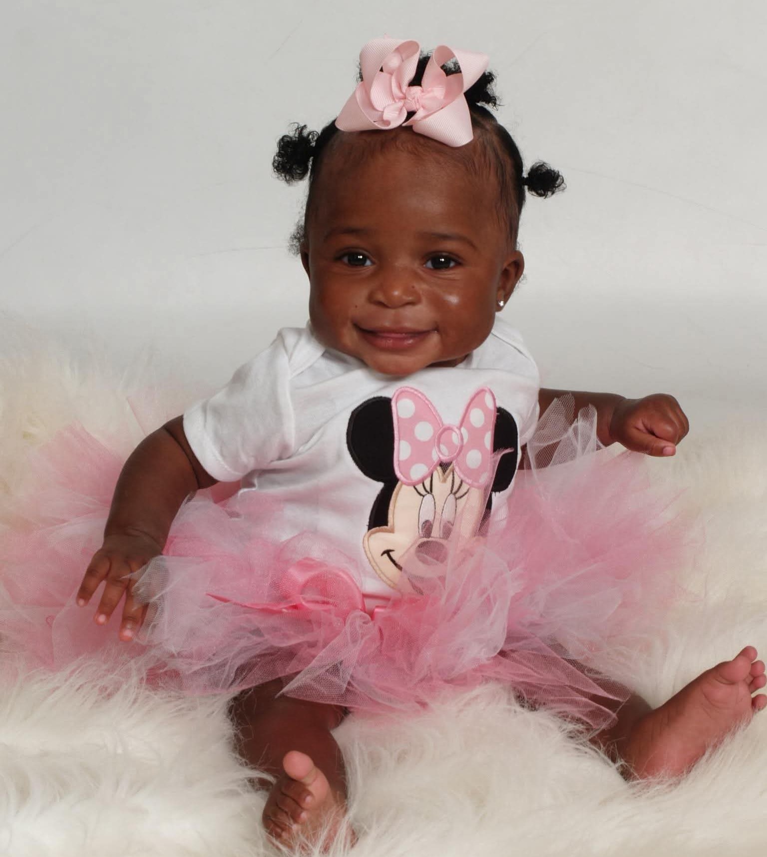 A smiling baby in a custom Minnie Mouse outfit handmade by Involving Memories